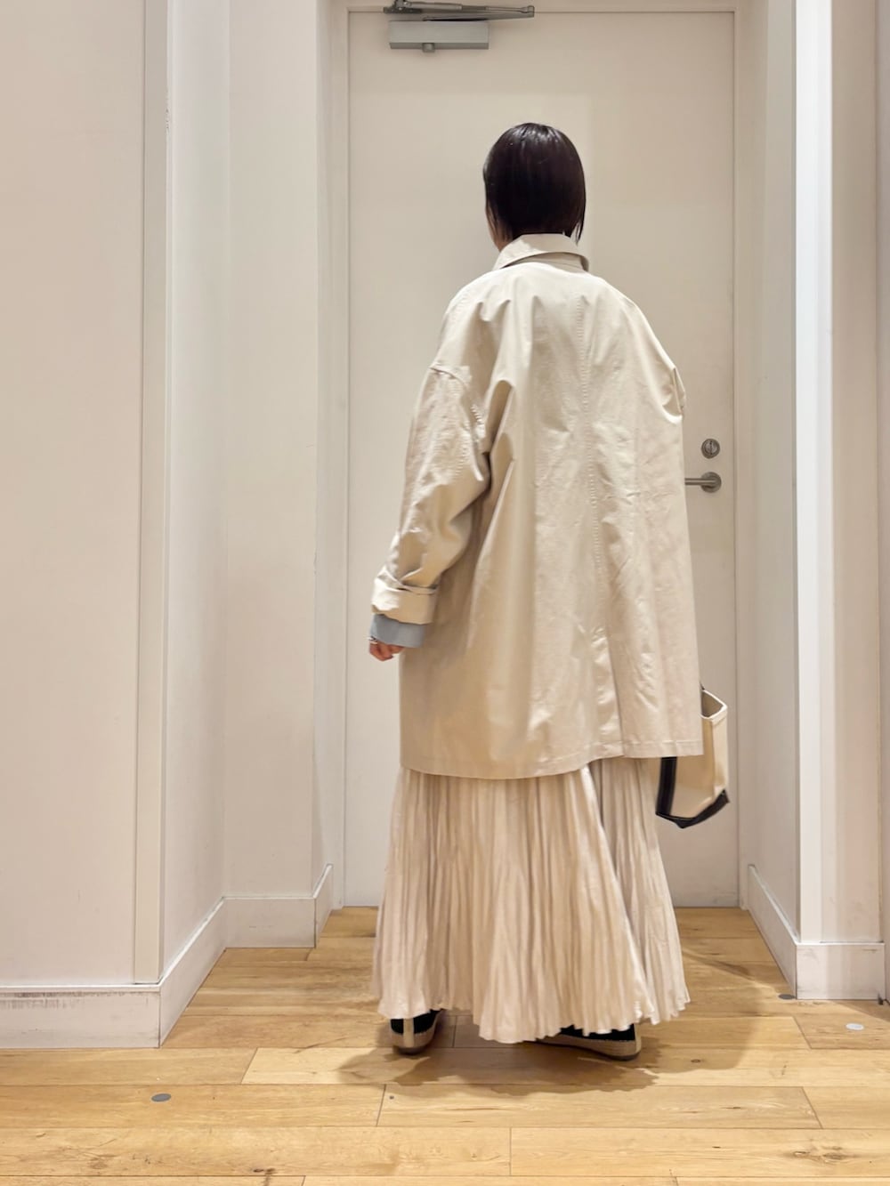 ホワイト系のTシャツ/カットソー、ベージュ系のステンカラーコート、ブルー系のベストを着用したレディースの春コーディネートの6枚目の写真