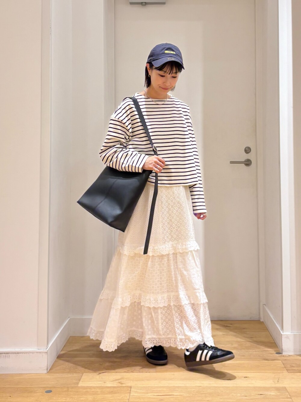 ホワイト系のTシャツ/カットソー、ホワイト系のスカート、ブラック系のショルダーバッグを着用したレディースの秋コーディネートの4枚目の写真