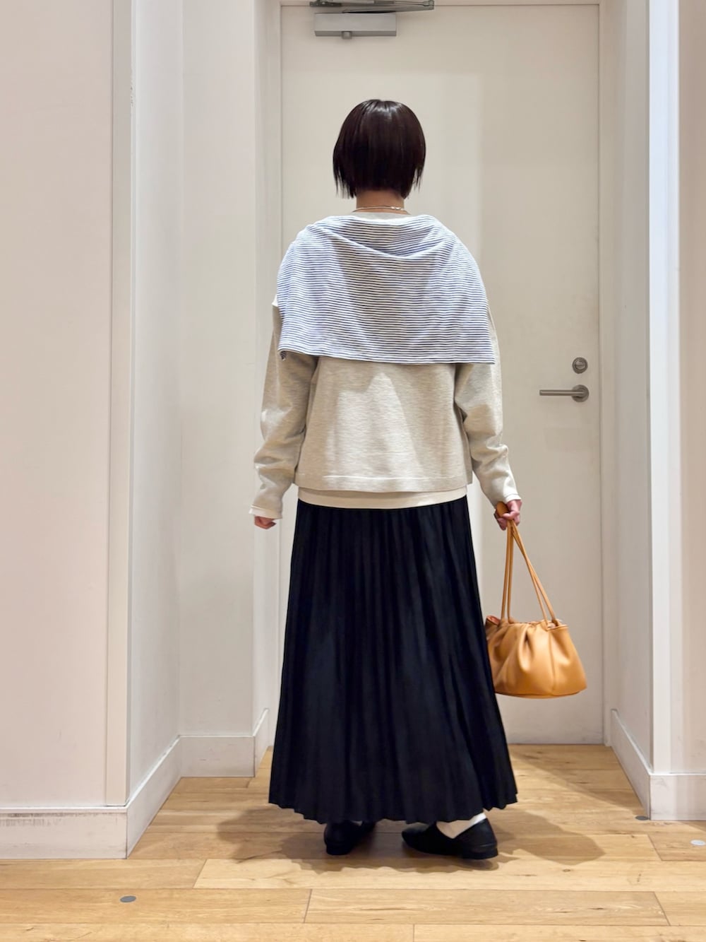 ベージュ系のTシャツ/カットソー、ベージュ系のカーディガン/ボレロ、ブラック系のスカートを着用したレディースの春コーディネートの7枚目の写真