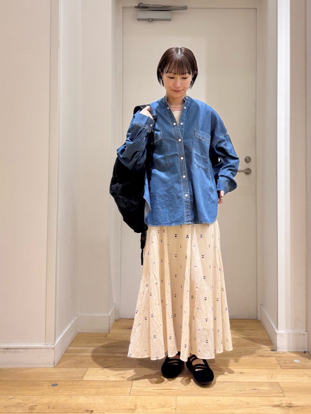 ブルー系のシャツ/ブラウス、ホワイト系のスカート、ブラック系のバックパック/リュックを着用したレディースの春コーディネートの4枚目の写真