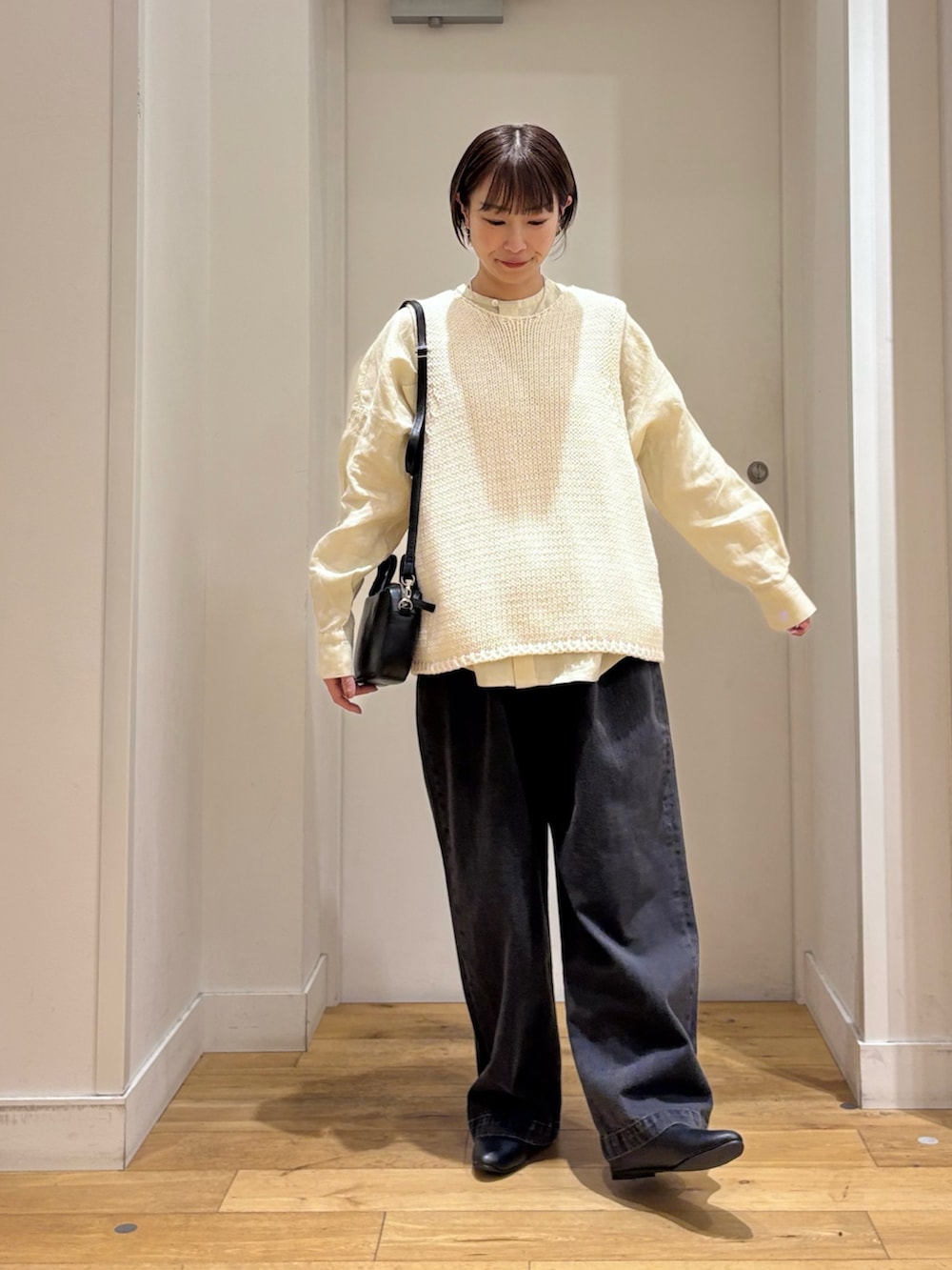 ホワイト系のベスト、ブラック系のデニムパンツ、ブラック系のパンプスを着用したレディースの春コーディネートの4枚目の写真