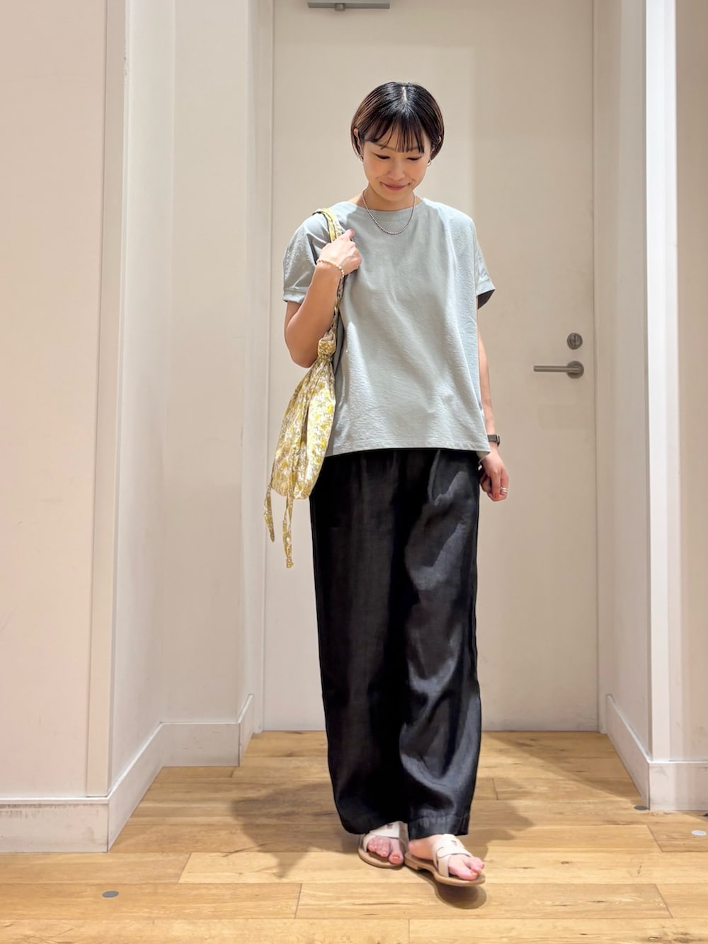 グリーン系のTシャツ/カットソー、ブラック系のデニムパンツ、イエロー系のトートバッグを着用したレディースの夏コーディネートの3枚目の写真