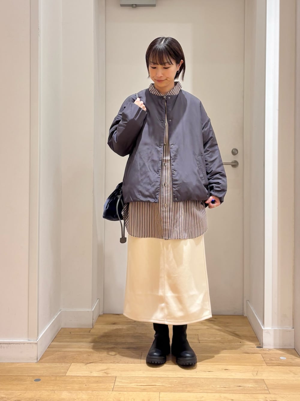 グレー系のブルゾン、グレー系のシャツ/ブラウス、ホワイト系のスカートを着用したレディースの冬コーディネートの2枚目の写真