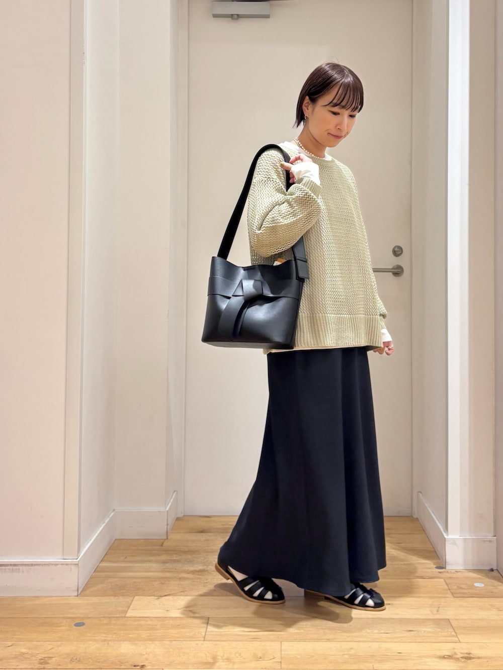 グリーン系のニット/セーター、ホワイト系のTシャツ/カットソー、ブルー系のスカートを着用したレディースの春コーディネートの5枚目の写真