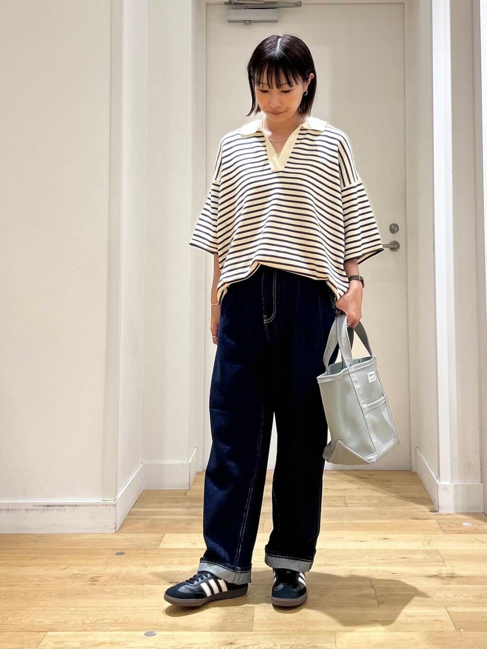 ホワイト系のニット/セーター、ブラック系のスニーカー、ブルー系のデニムパンツを着用したレディースの夏コーディネートの2枚目の写真