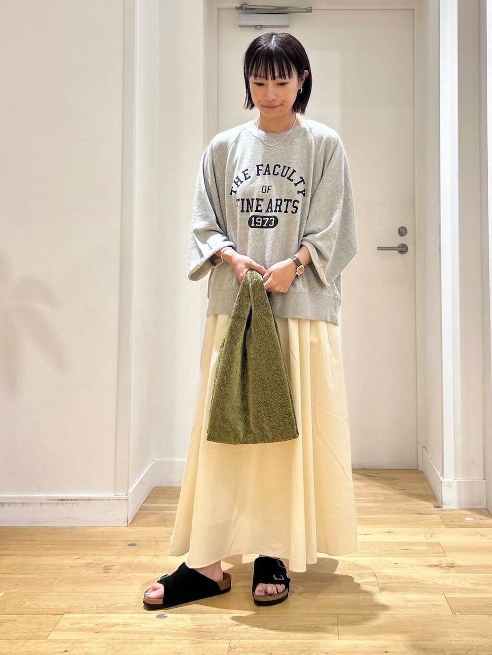 ホワイト系のスカート、ブラック系のサンダル、グレー系のTシャツ/カットソーを着用したレディースの夏コーディネートの2枚目の写真