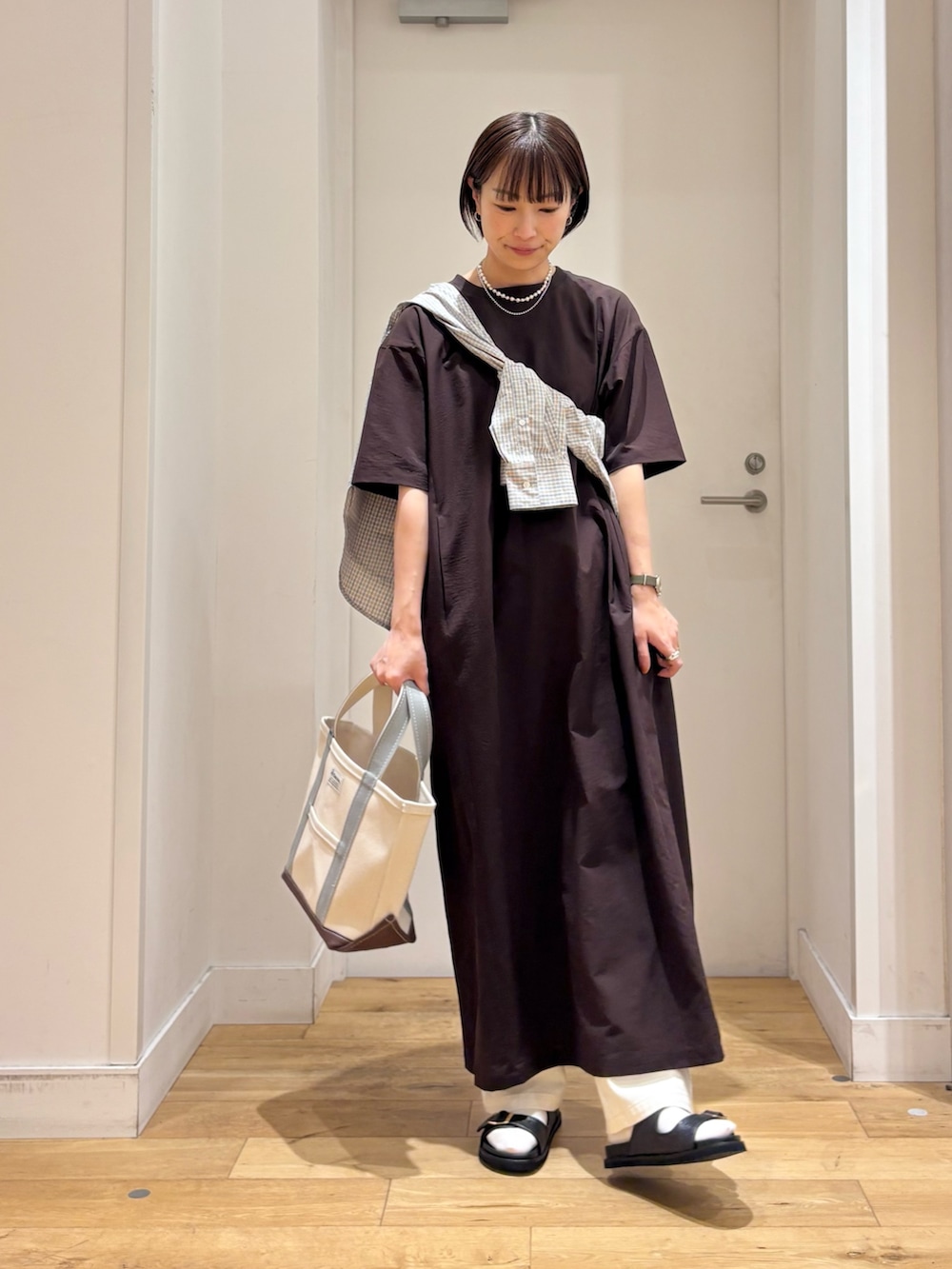 ブラウン系のワンピース、ブルー系のシャツ/ブラウス、グリーン系のトートバッグを着用したレディースの春コーディネートの3枚目の写真