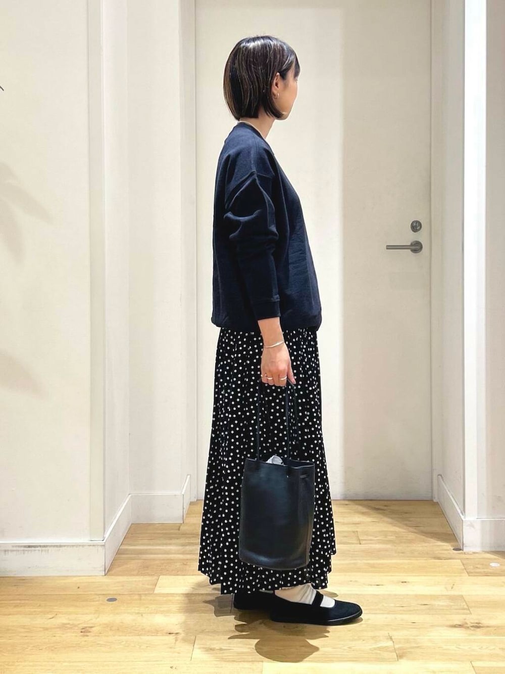 ブラック系のスニーカー、ブラック系のショルダーバッグ、ブラック系のスカートを着用したレディースの秋コーディネートの4枚目の写真