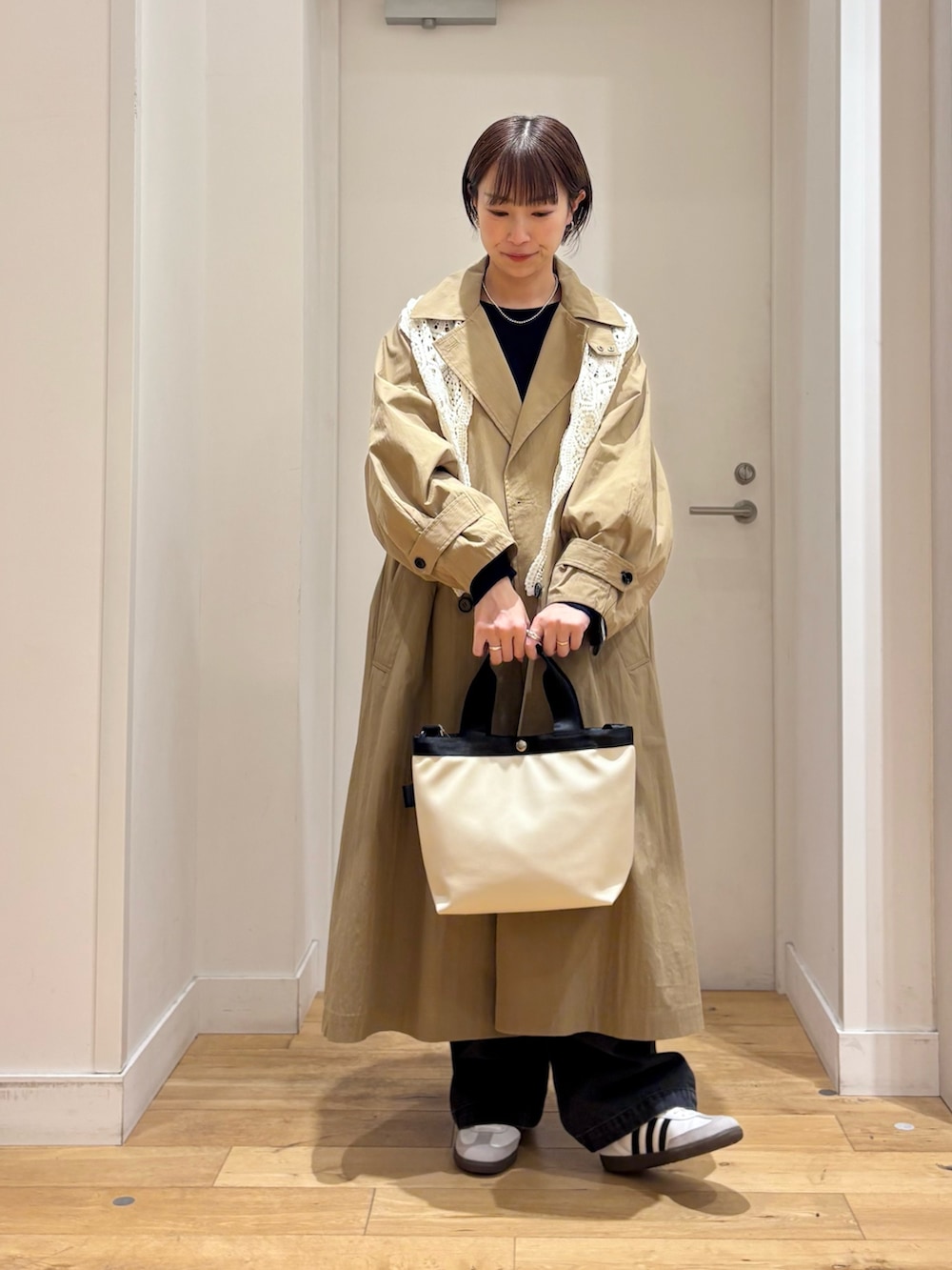 ブルー系のニット/セーター、ブラック系のデニムパンツ、ホワイト系のハンドバッグを着用したレディースの春コーディネートの2枚目の写真