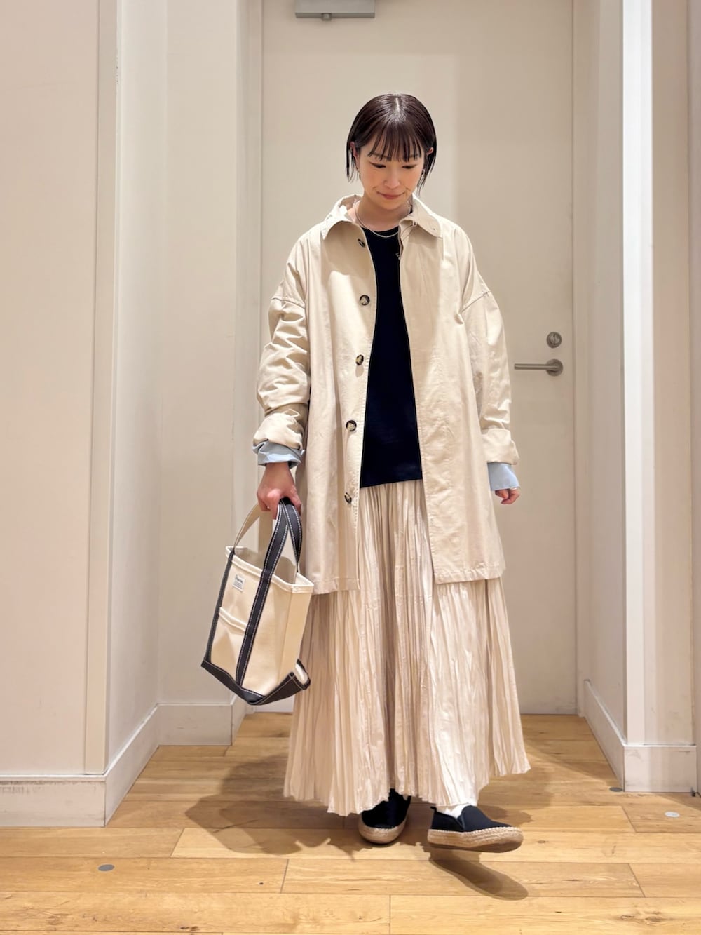 ホワイト系のTシャツ/カットソー、ベージュ系のステンカラーコート、ブルー系のベストを着用したレディースの春コーディネートの2枚目の写真