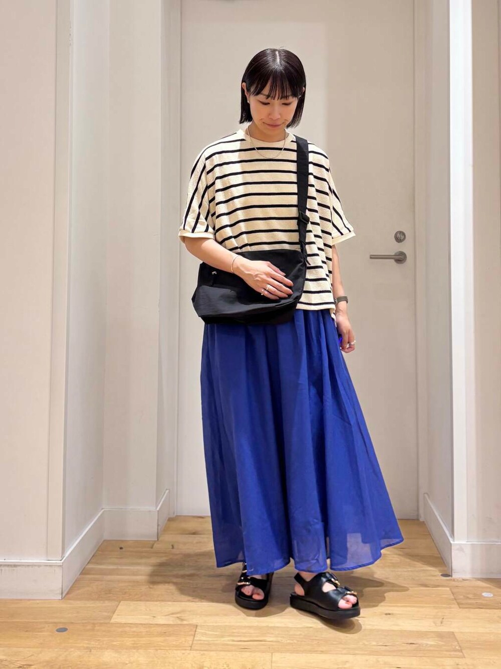 ブルー系のスカート、ブラック系のサンダル、ブラック系のショルダーバッグを着用したレディースの夏コーディネートの2枚目の写真