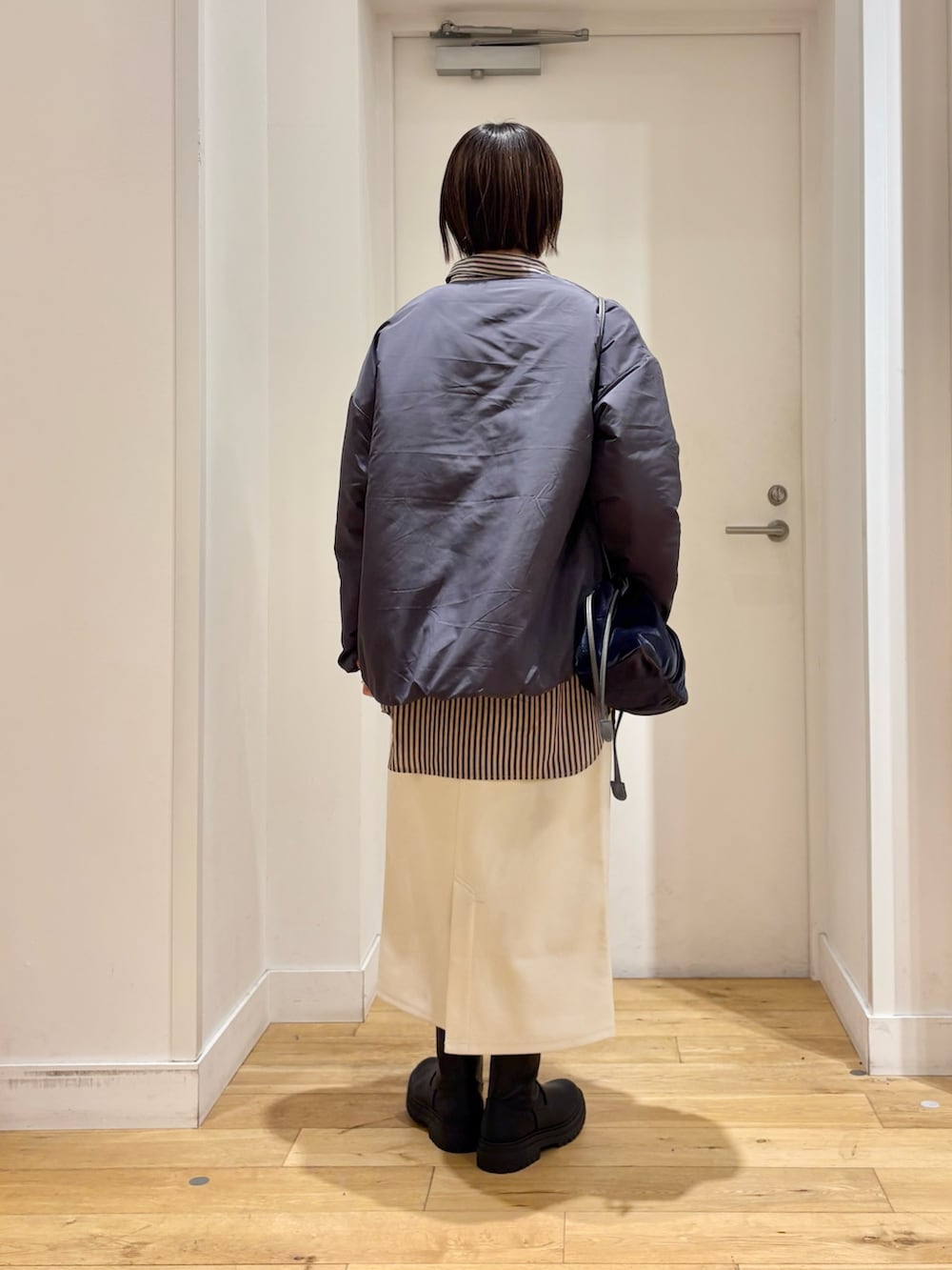 グレー系のブルゾン、グレー系のシャツ/ブラウス、ホワイト系のスカートを着用したレディースの冬コーディネートの4枚目の写真