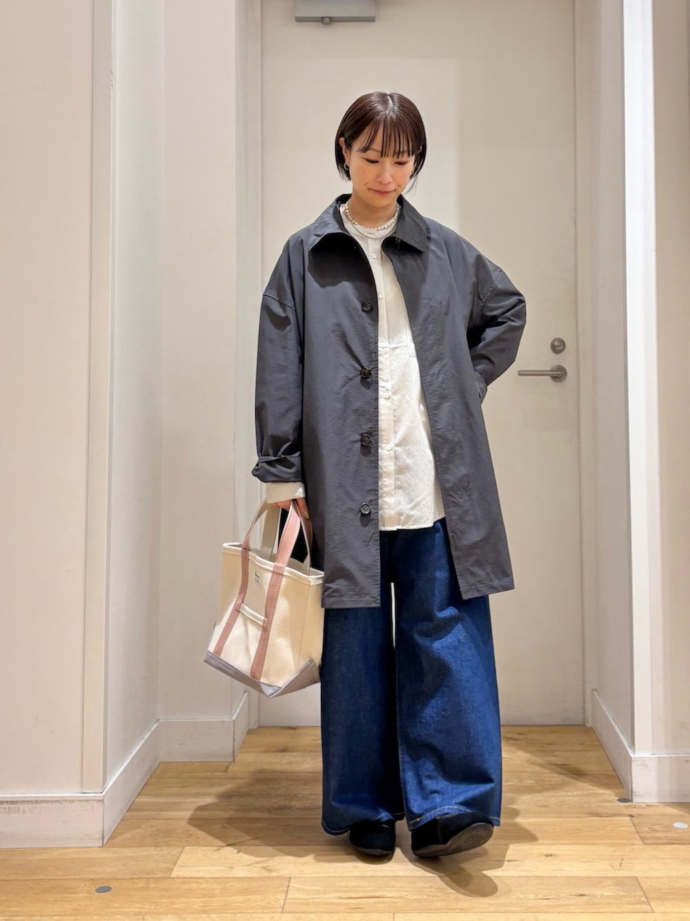 グレー系のステンカラーコート、グレー系のシャツ/ブラウス、ブルー系のデニムパンツを着用したレディースの春コーディネートの3枚目の写真