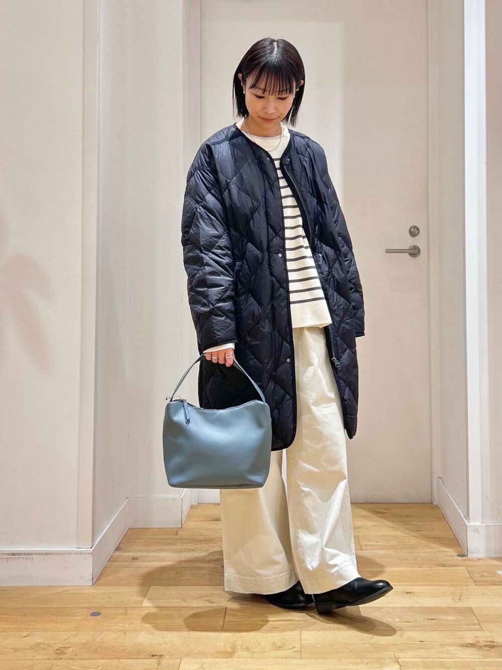ブラック系のダウンジャケット/コート、ブルー系のショルダーバッグ、ブラック系のブーツを着用したレディースの冬コーディネートの4枚目の写真