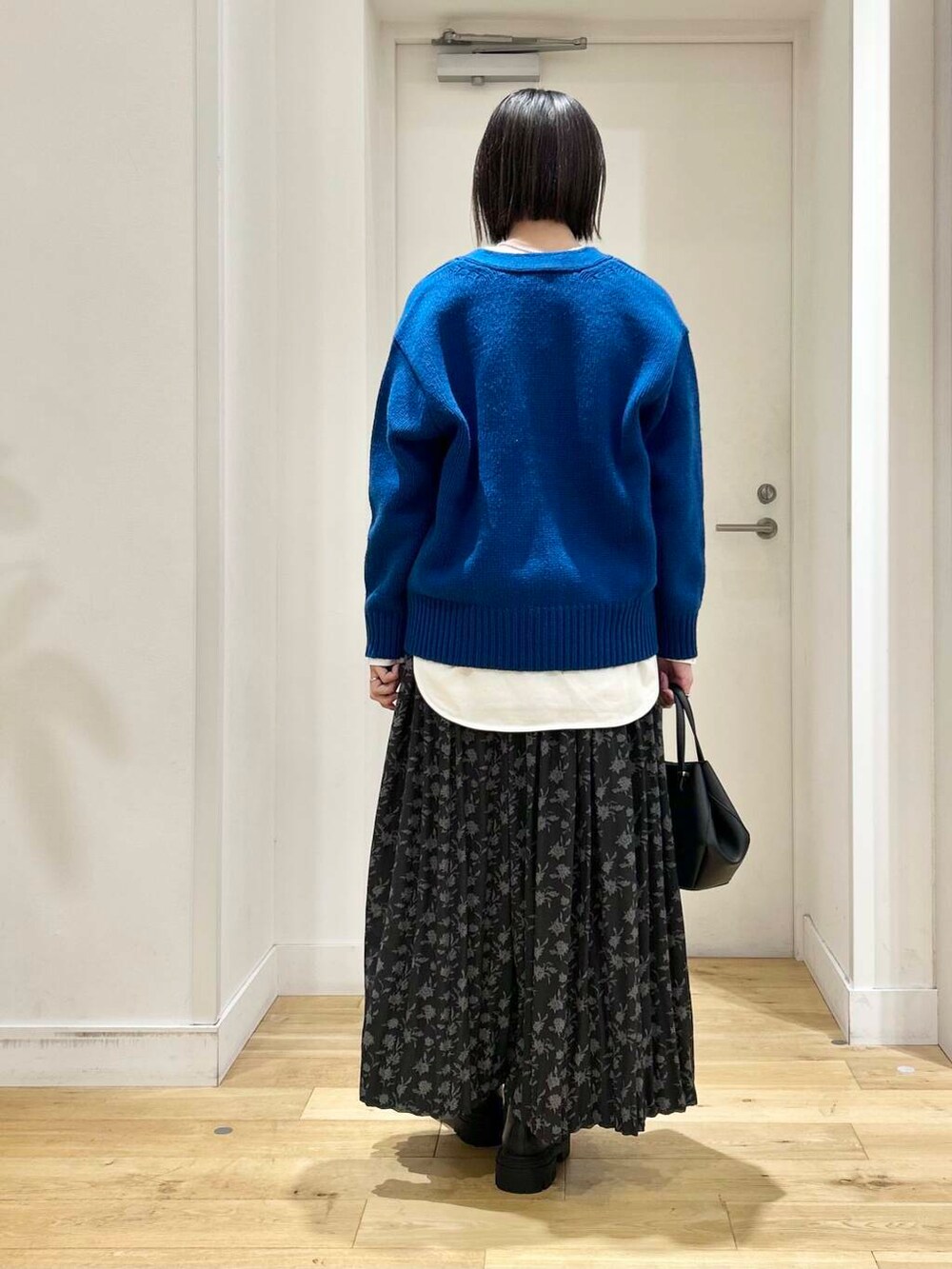 ブラック系のショルダーバッグ、ブラック系のブーツ、ブルー系のカーディガン/ボレロを着用したレディースの冬コーディネートの5枚目の写真