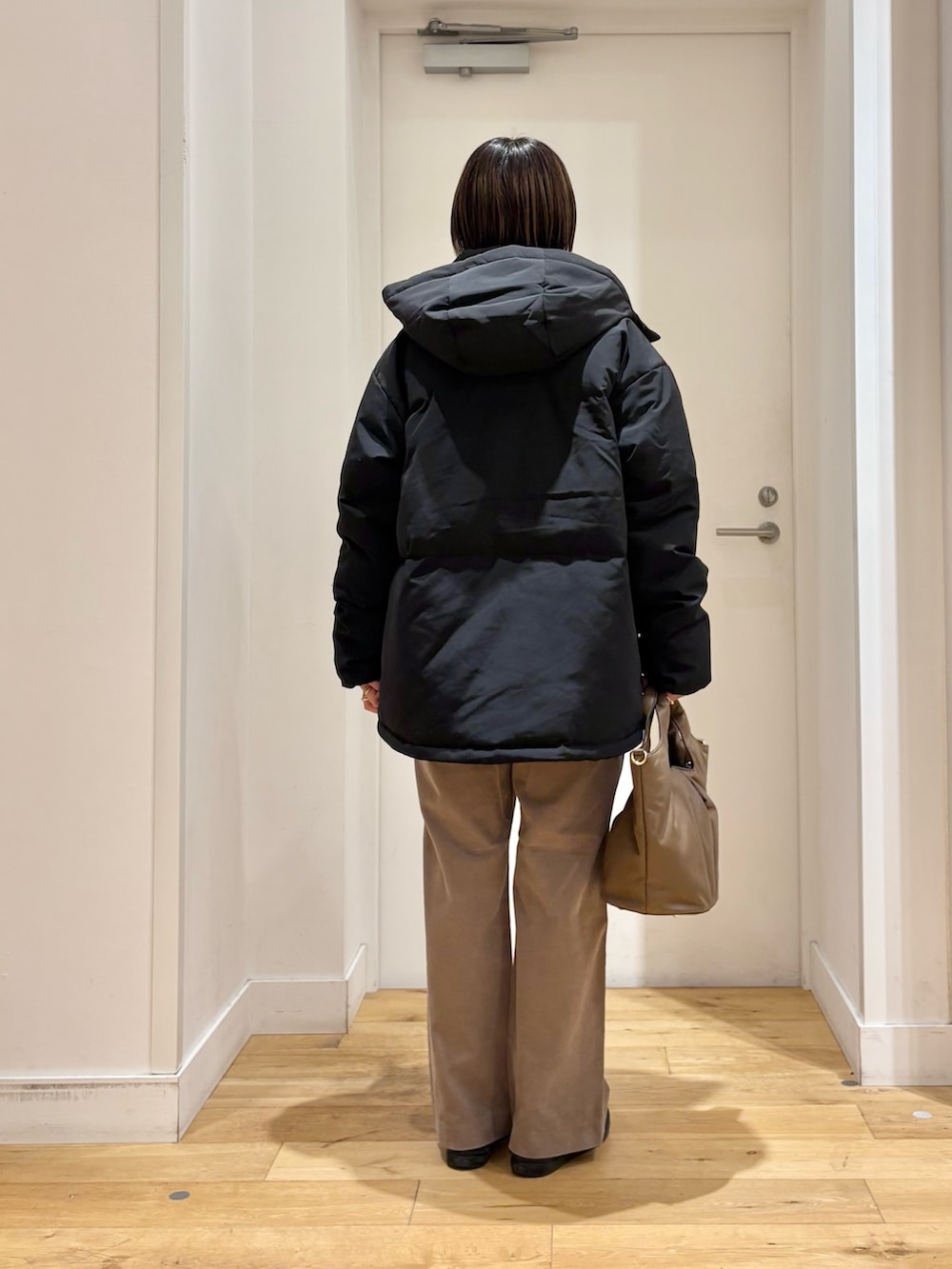 ブラック系のダウンジャケット/コート、ベージュ系のニット/セーター、ホワイト系のシャツ/ブラウスを着用したレディースの冬コーディネートの4枚目の写真