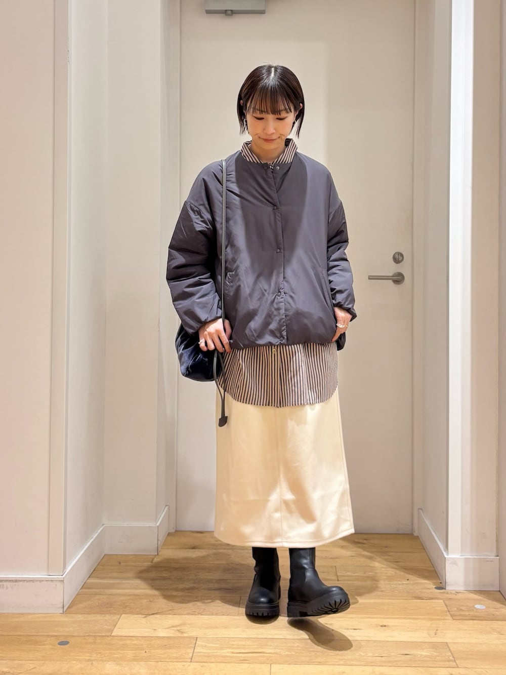 グレー系のブルゾン、グレー系のシャツ/ブラウス、ホワイト系のスカートを着用したレディースの冬コーディネートの6枚目の写真