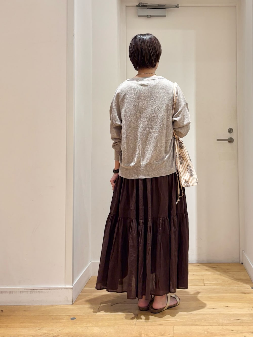 ブラウン系のワンピース、ベージュ系のカーディガン/ボレロ、ゴールド系のサンダルを着用したレディースの夏コーディネートの7枚目の写真