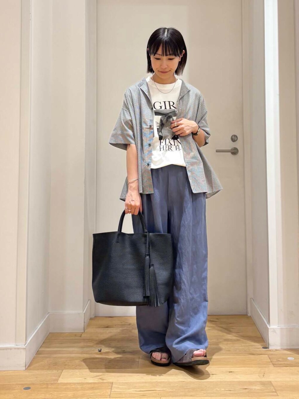 ブラック系のトートバッグ、グレー系のサンダル、ブルー系のその他パンツを着用したレディースの夏コーディネートの2枚目の写真