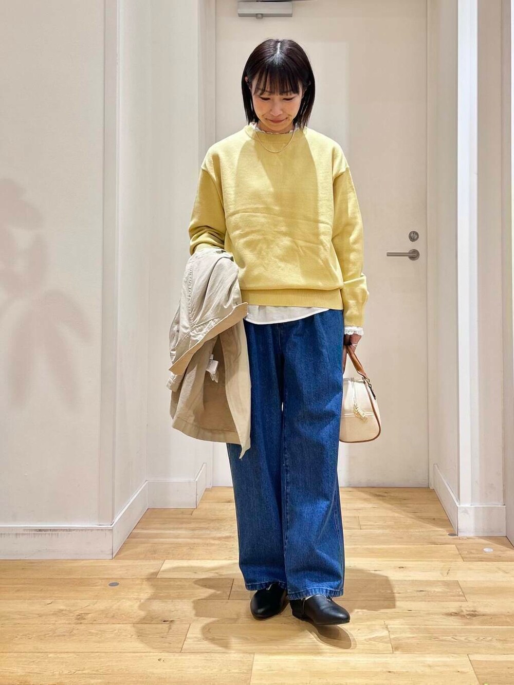 ホワイト系のシャツ/ブラウス、イエロー系のニット/セーター、ブルー系のデニムパンツを着用したレディースの冬コーディネートの7枚目の写真