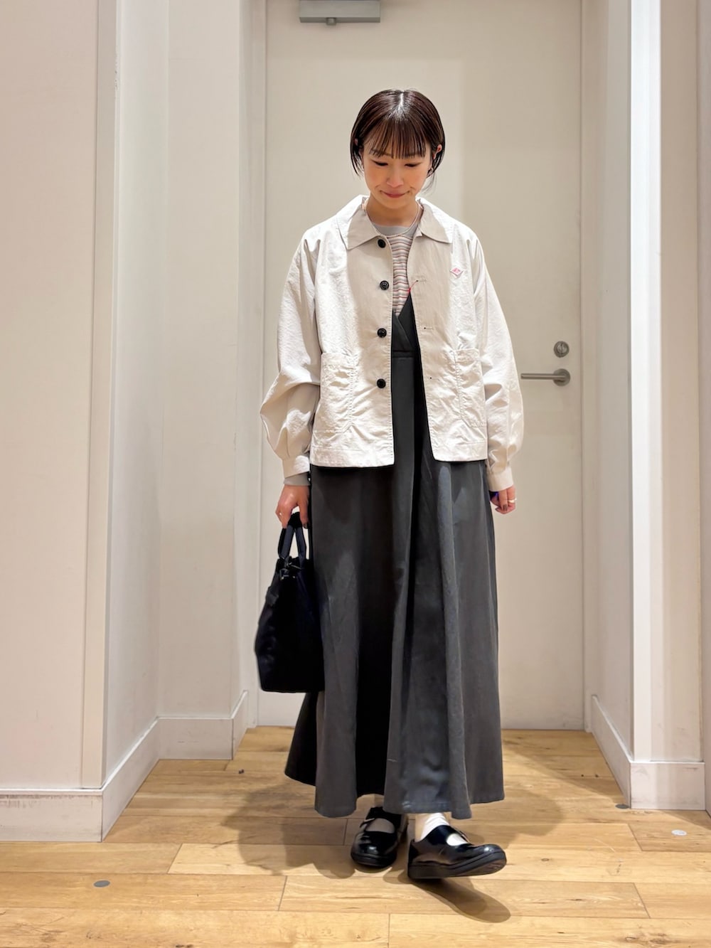 レッド系のスウェット、ベージュ系のテーラードジャケット、グリーン系のワンピースを着用したレディースの春コーディネートの3枚目の写真