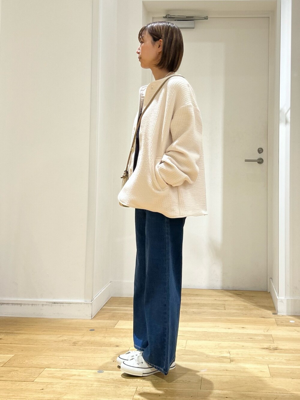 ホワイト系のノーカラージャケット、ホワイト系のショルダーバッグ、ブルー系のその他パンツを着用したレディースの春コーディネートの3枚目の写真