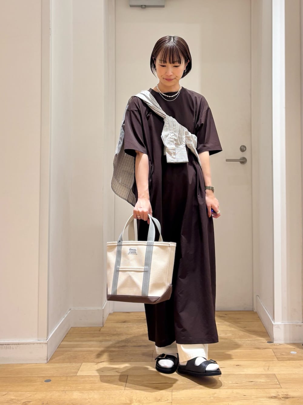 ブラウン系のワンピース、ブルー系のシャツ/ブラウス、グリーン系のトートバッグを着用したレディースの春コーディネートの2枚目の写真