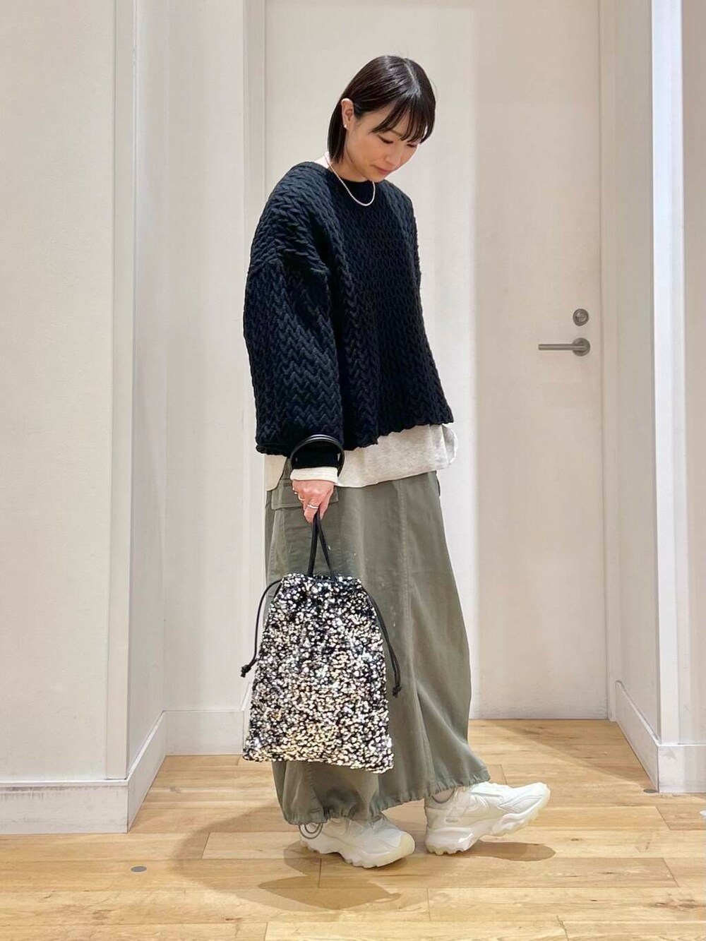 グリーン系のスカート、ホワイト系のスニーカー、シルバー系のトートバッグを着用したレディースの冬コーディネートの3枚目の写真