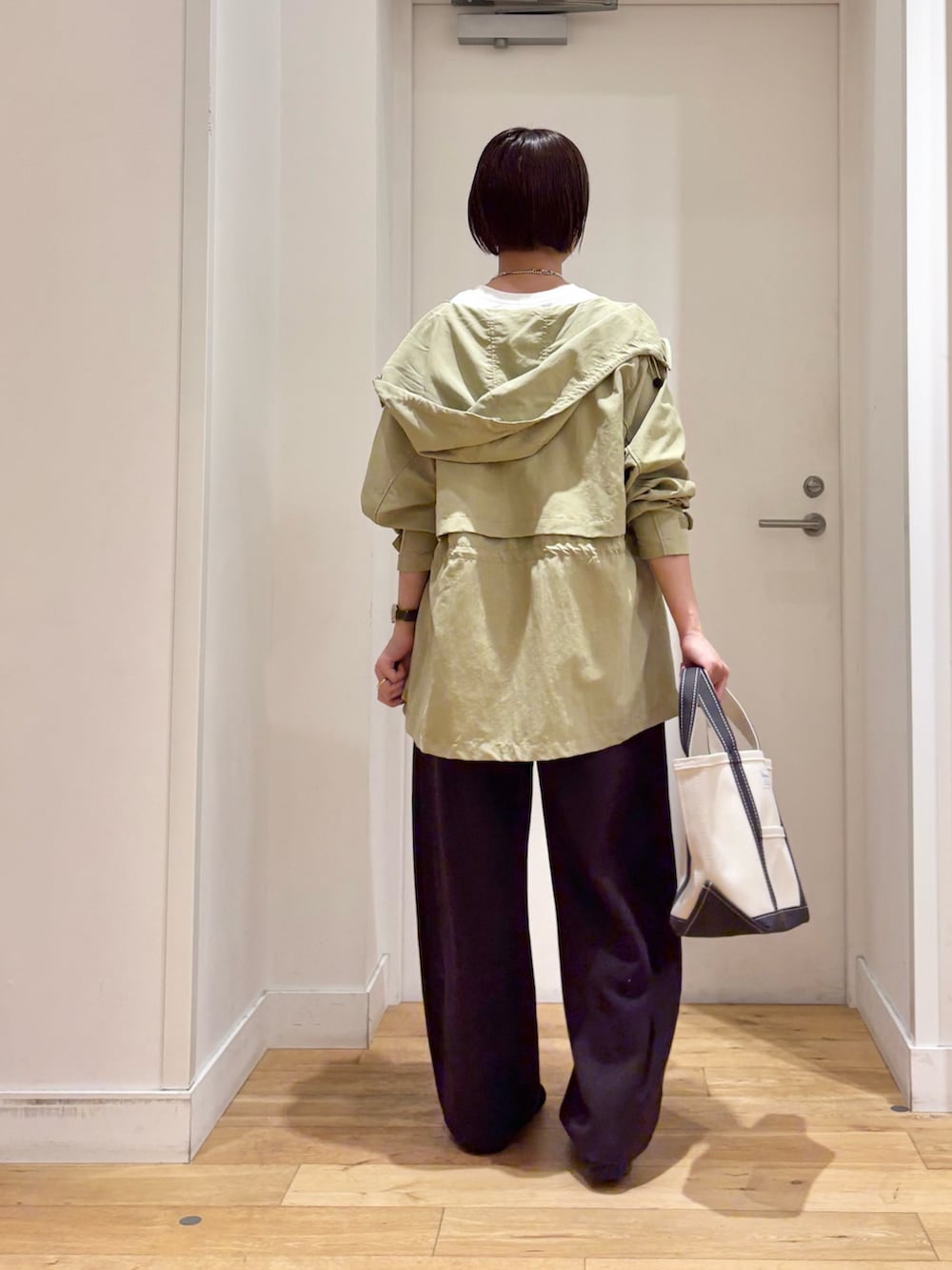 グリーン系のマウンテンパーカー、ホワイト系のTシャツ/カットソー、ブラック系のスニーカーを着用したレディースの春コーディネートの5枚目の写真