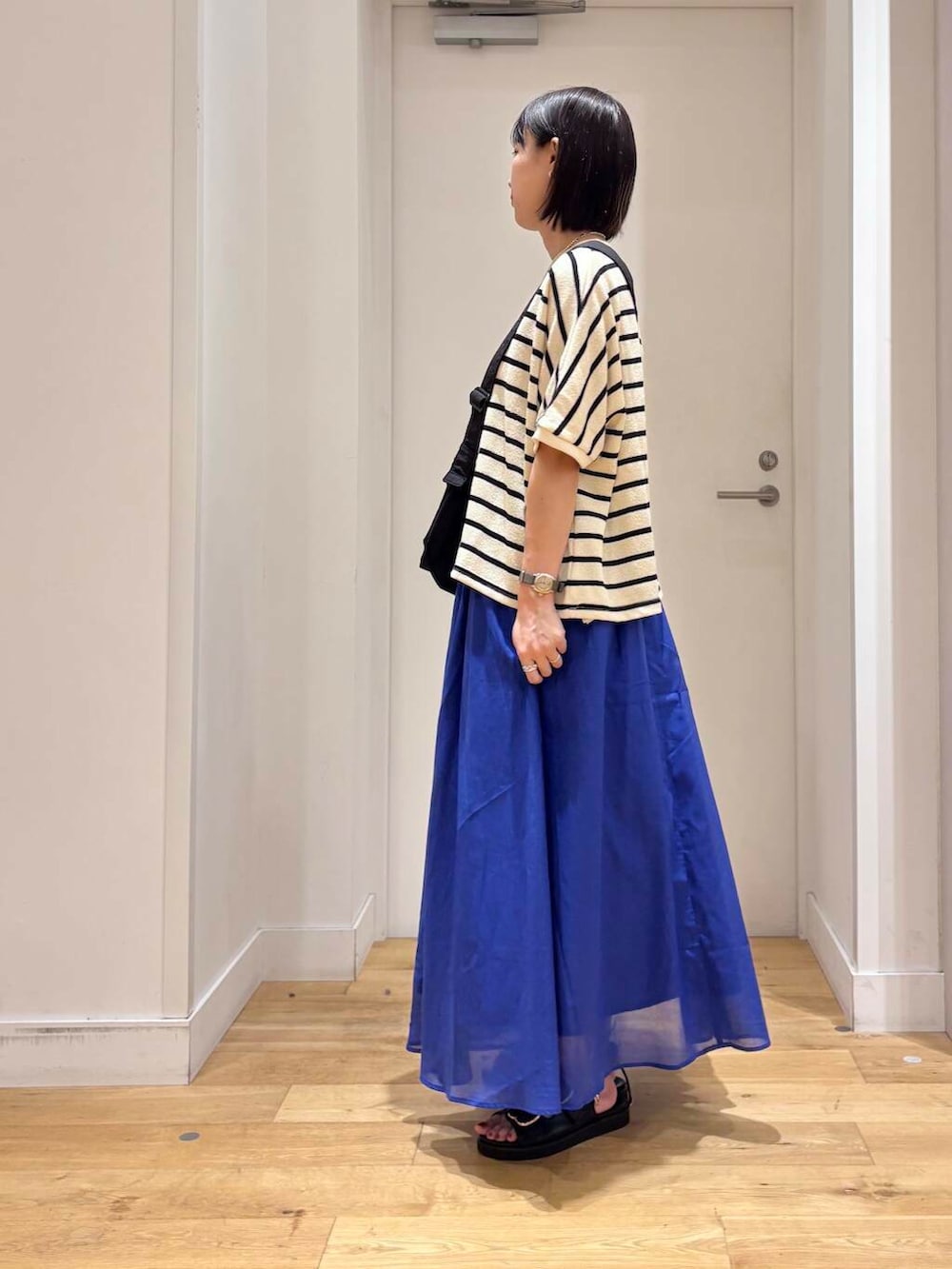 ブルー系のスカート、ブラック系のサンダル、ブラック系のショルダーバッグを着用したレディースの夏コーディネートの4枚目の写真