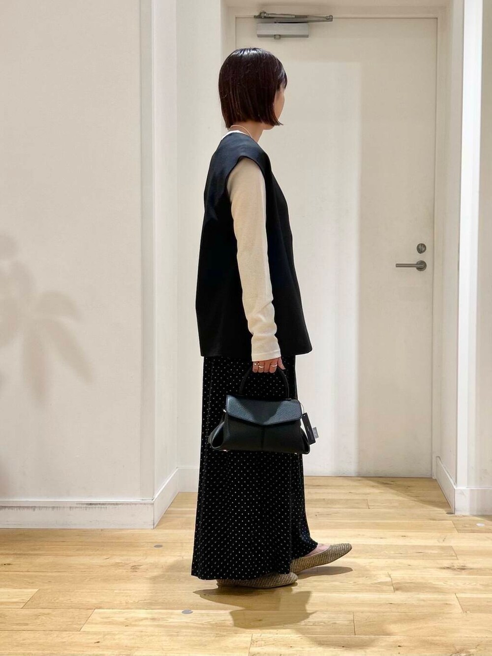 ベージュ系のパンプス、ブラック系のベスト、ブラック系のショルダーバッグを着用したレディースの夏コーディネートの3枚目の写真