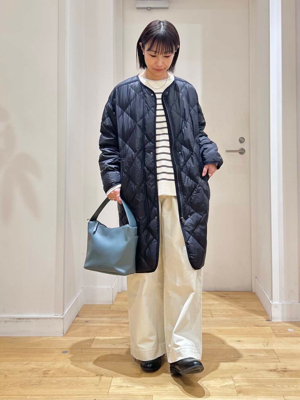 ブラック系のダウンジャケット/コート、ブルー系のショルダーバッグ、ブラック系のブーツを着用したレディースの冬コーディネートの2枚目の写真