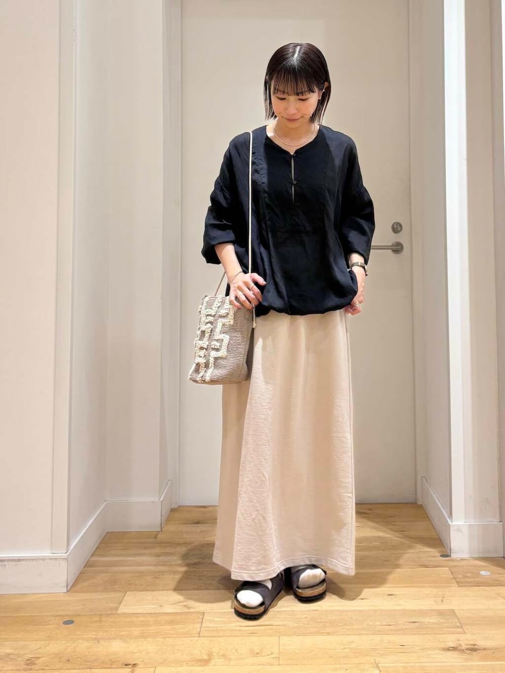 グレー系のショルダーバッグ、ブラック系のチュニック、グレー系のサンダルを着用したレディースの春コーディネートの3枚目の写真