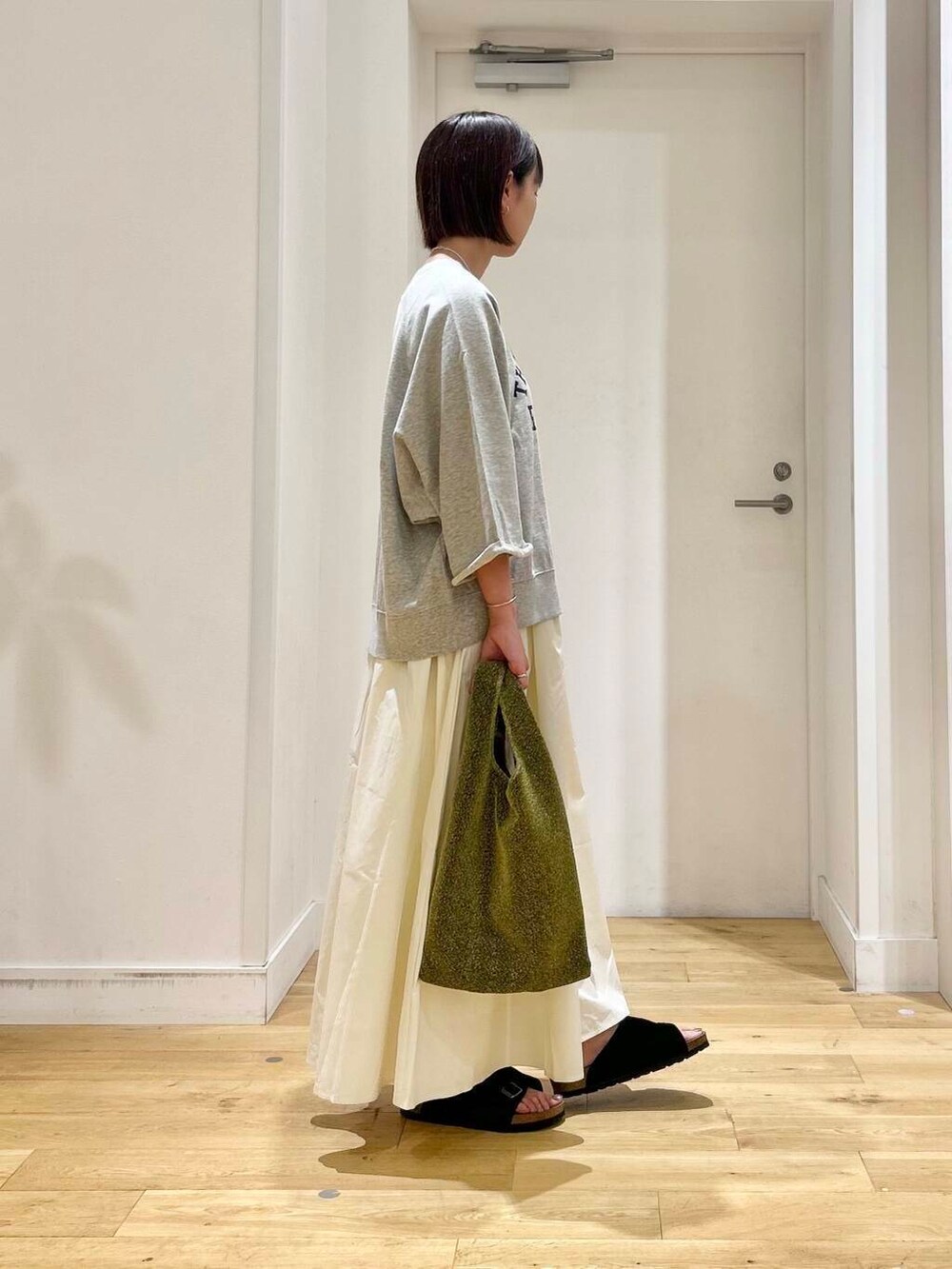 ホワイト系のスカート、ブラック系のサンダル、グレー系のTシャツ/カットソーを着用したレディースの夏コーディネートの3枚目の写真