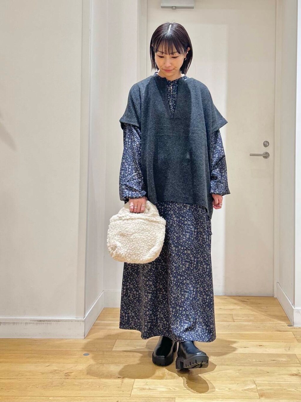 ブラック系のブーツ、ベージュ系のハンドバッグ、ブルー系のワンピースを着用したレディースの冬コーディネートの3枚目の写真