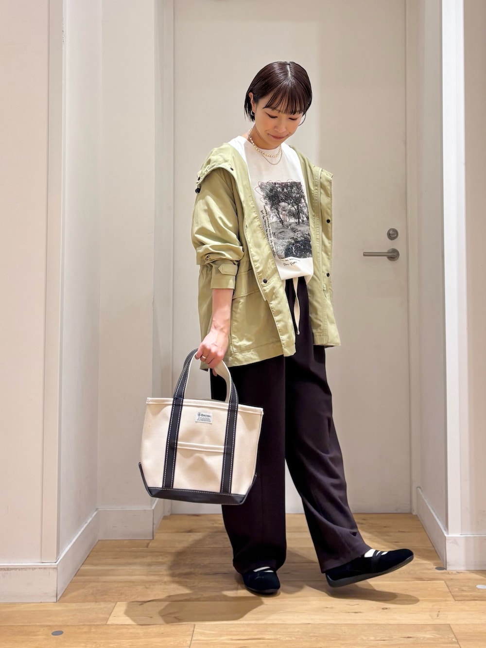 グリーン系のマウンテンパーカー、ホワイト系のTシャツ/カットソー、ブラック系のスニーカーを着用したレディースの春コーディネートの4枚目の写真