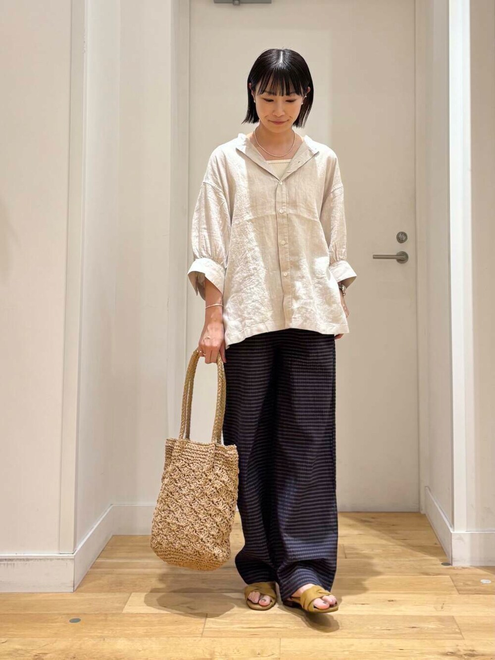 ベージュ系のシャツ/ブラウス、ベージュ系のトートバッグ、イエロー系のサンダルを着用したレディースの夏コーディネートの2枚目の写真