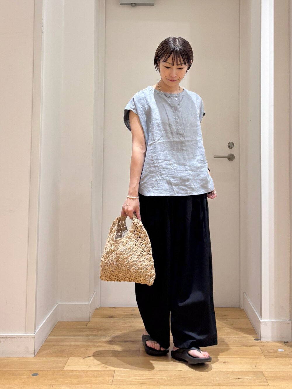ブルー系のシャツ/ブラウス、ブラック系のその他パンツ、ベージュ系のハンドバッグを着用したレディースの夏コーディネートの3枚目の写真