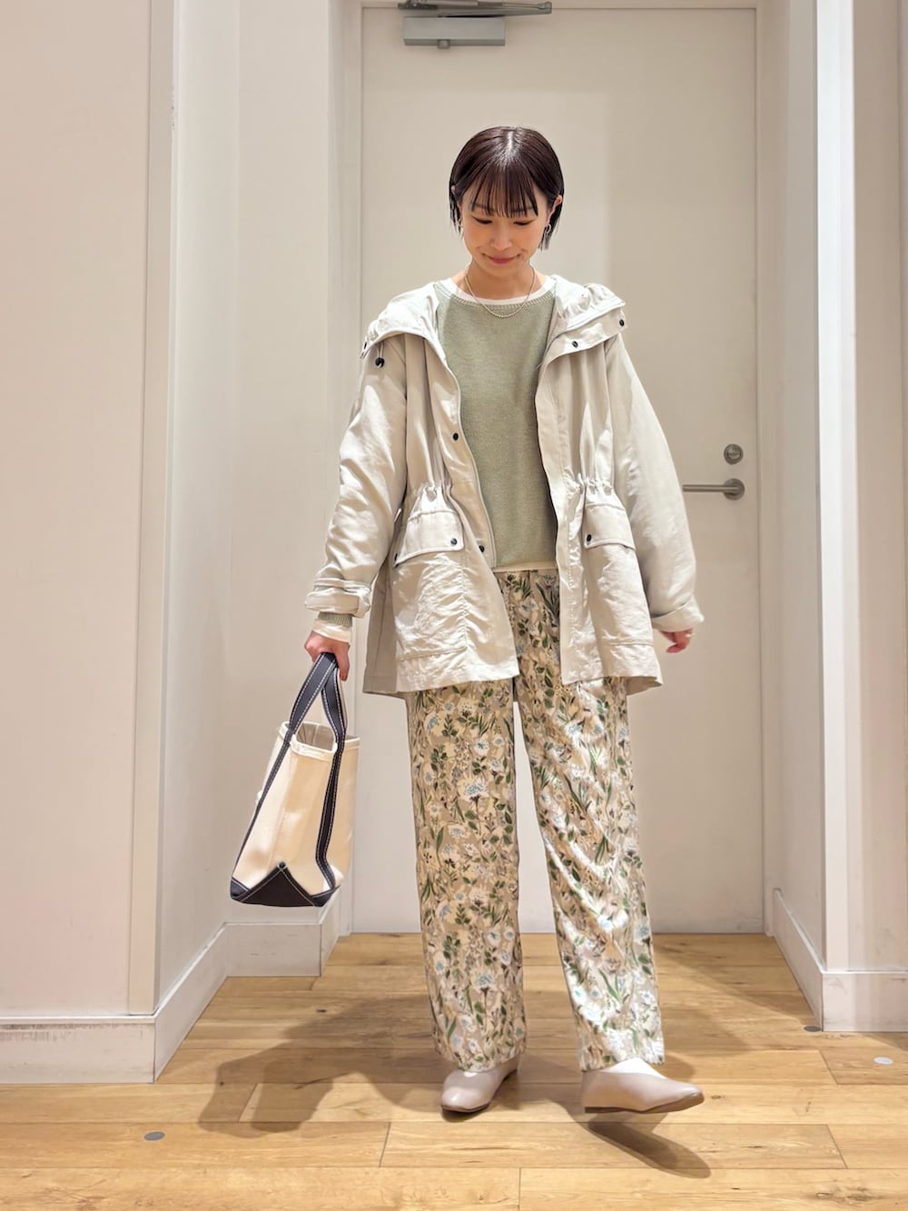 ベージュ系のマウンテンパーカー、グリーン系のニット/セーター、グレー系のパンプスを着用したレディースの春コーディネートの2枚目の写真