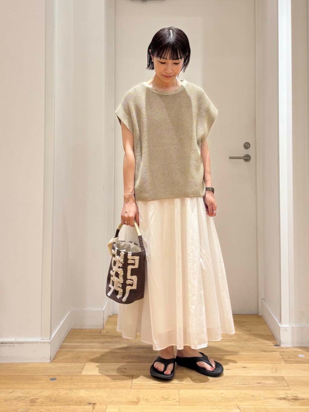 ブラック系のサンダル、ブラウン系のショルダーバッグ、ホワイト系のワンピースを着用したレディースの夏コーディネートの3枚目の写真