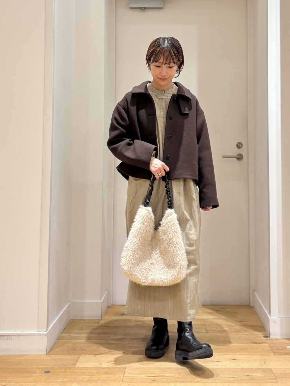 ブラウン系のその他アウター、ベージュ系のワンピース、ブラック系のブーツを着用したレディースの秋コーディネートの2枚目の写真