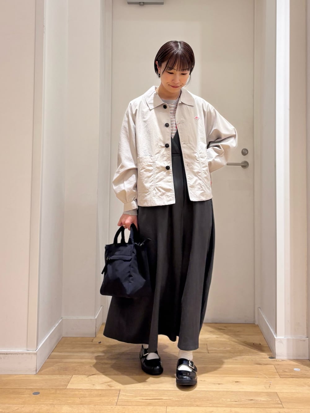 レッド系のスウェット、ベージュ系のテーラードジャケット、グリーン系のワンピースを着用したレディースの春コーディネートの2枚目の写真