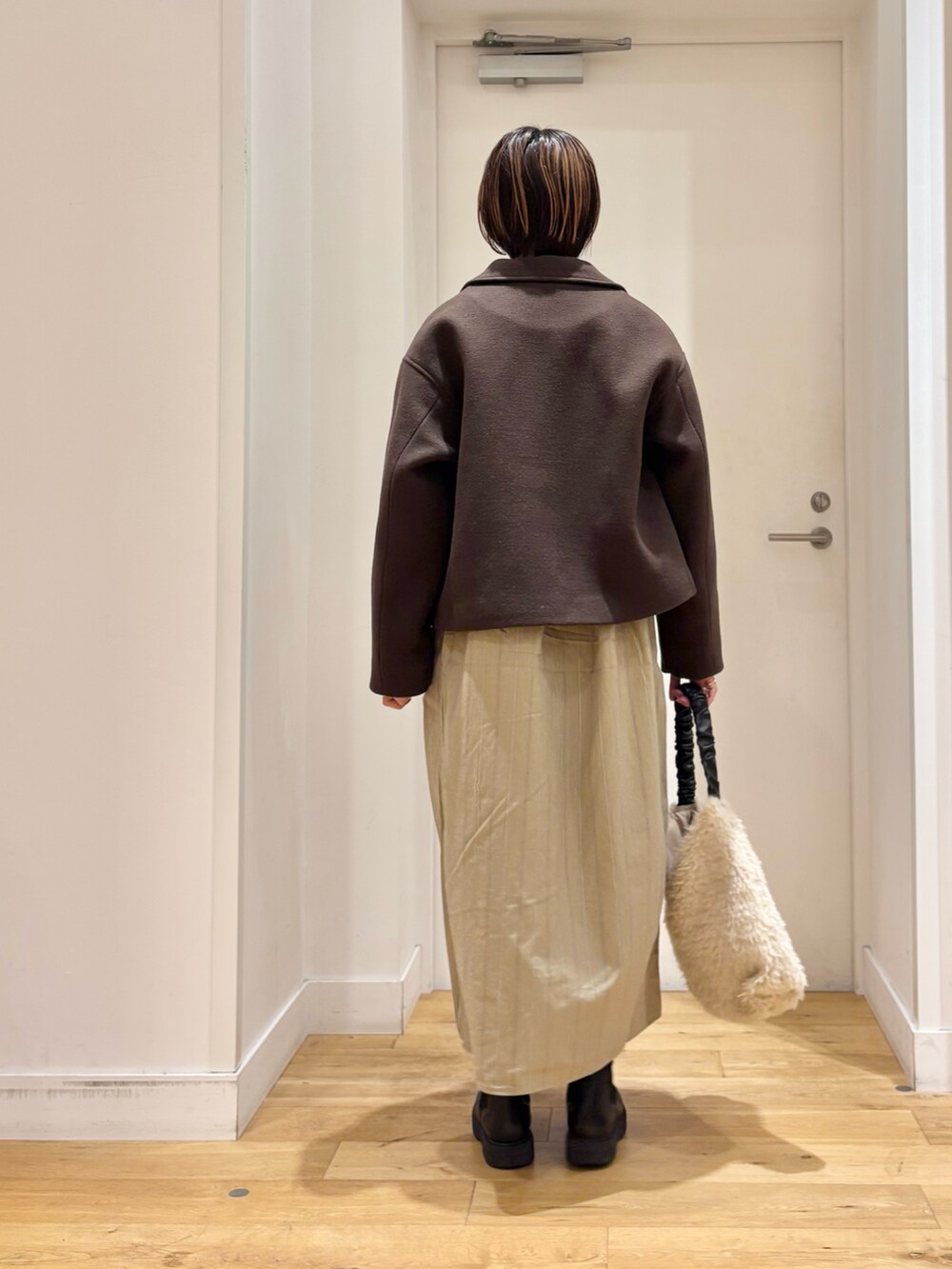 ブラウン系のその他アウター、ベージュ系のワンピース、ブラック系のブーツを着用したレディースの秋コーディネートの5枚目の写真