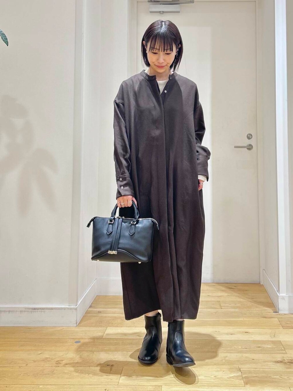 グレー系のその他アウター、ブラック系のボストンバッグ、ブラック系のブーツを着用したレディースの冬コーディネートの6枚目の写真