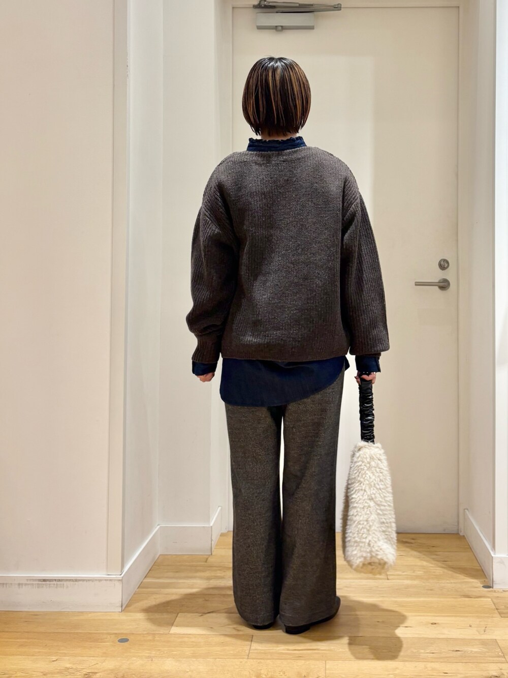 ブラウン系のニット/セーター、グレー系のその他パンツ、ブルー系のシャツ/ブラウスを着用したレディースの秋コーディネートの5枚目の写真