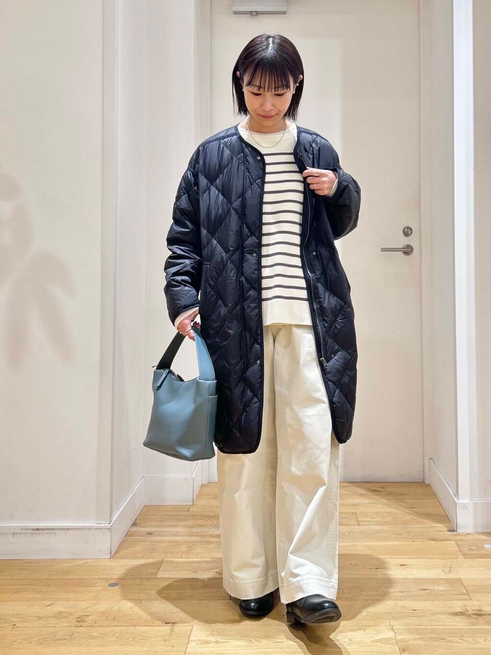 ブラック系のダウンジャケット/コート、ブルー系のショルダーバッグ、ブラック系のブーツを着用したレディースの冬コーディネートの3枚目の写真