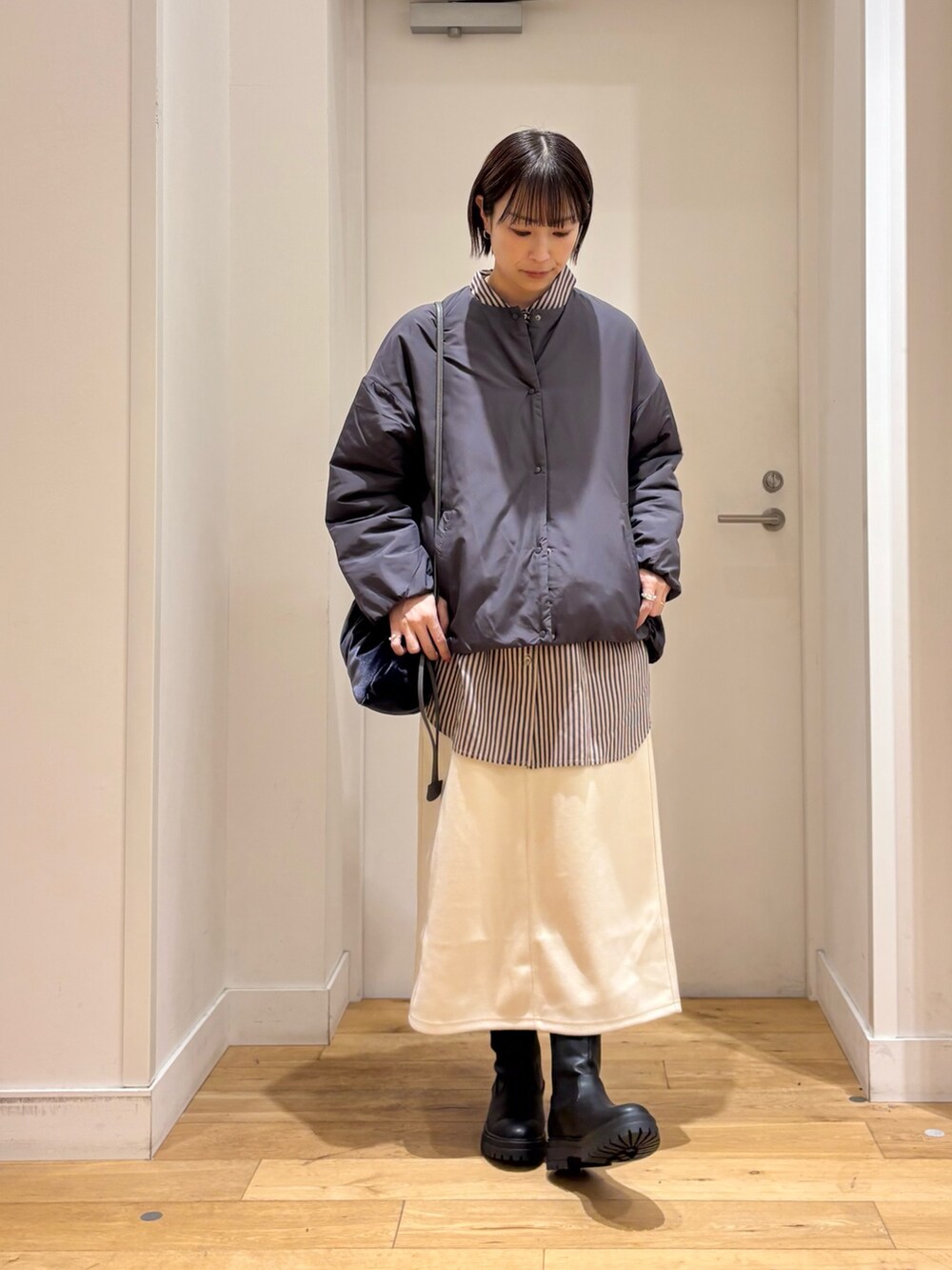 グレー系のブルゾン、グレー系のシャツ/ブラウス、ホワイト系のスカートを着用したレディースの冬コーディネートの5枚目の写真