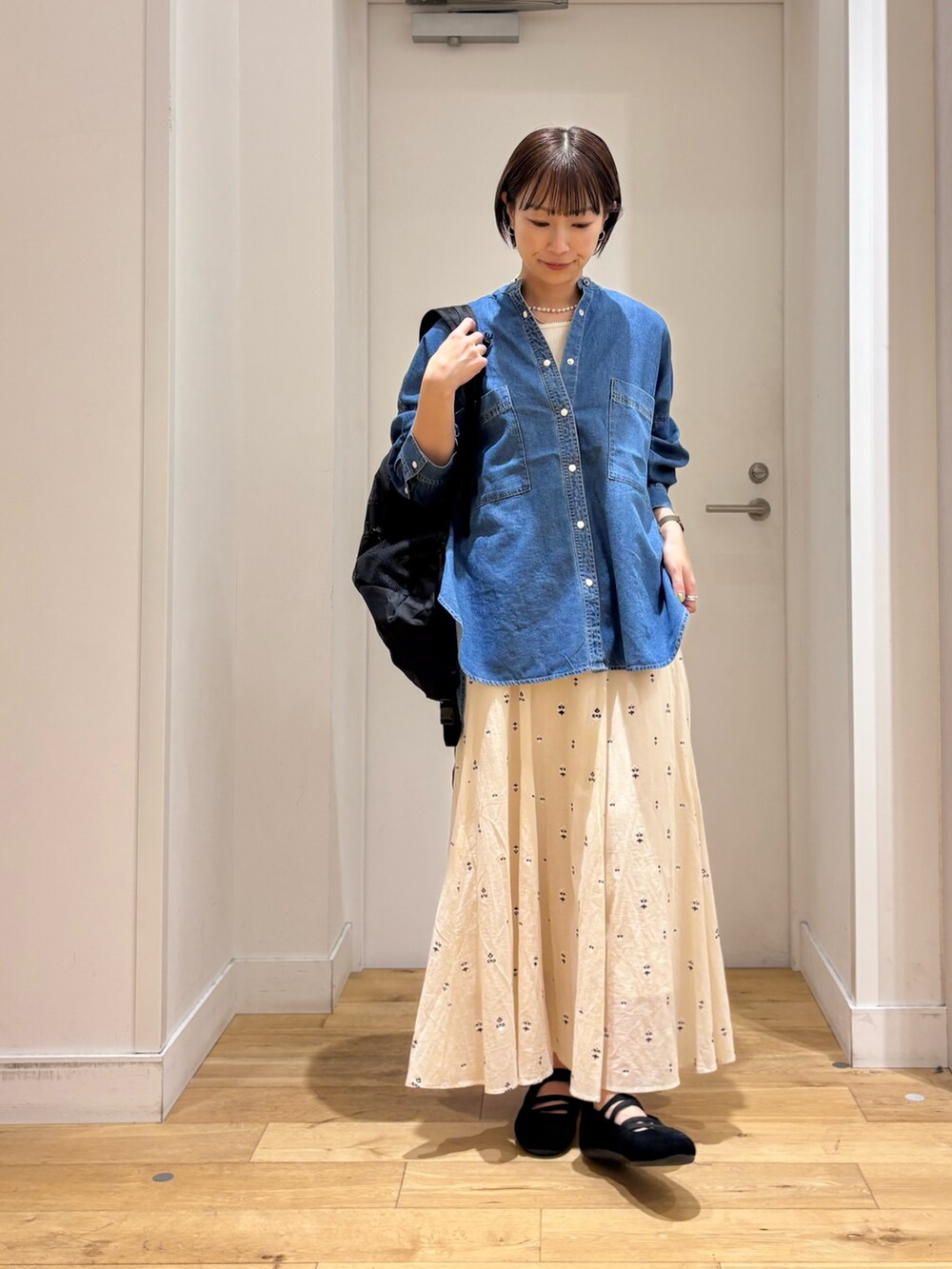 ブルー系のシャツ/ブラウス、ホワイト系のスカート、ブラック系のバックパック/リュックを着用したレディースの春コーディネートの5枚目の写真