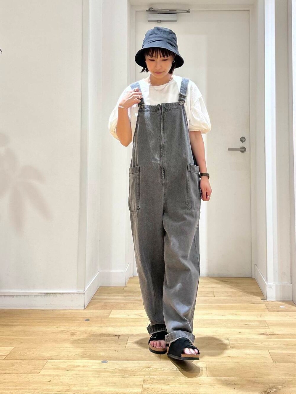 ブラック系のサンダル、グレー系のサロペット/オーバーオール、ホワイト系のTシャツ/カットソーを着用したレディースの夏コーディネートの2枚目の写真