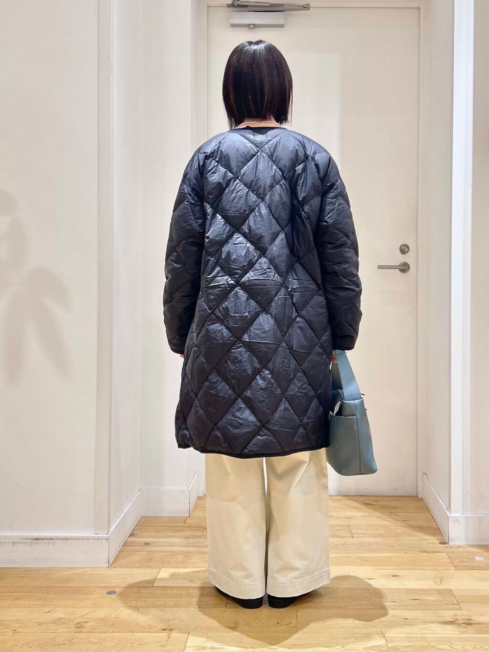 ブラック系のダウンジャケット/コート、ブルー系のショルダーバッグ、ブラック系のブーツを着用したレディースの冬コーディネートの7枚目の写真